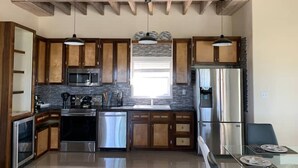 Una cucina moderna con mobili in legno, elettrodomestici in acciaio inossidabile e lampade a sospensione.