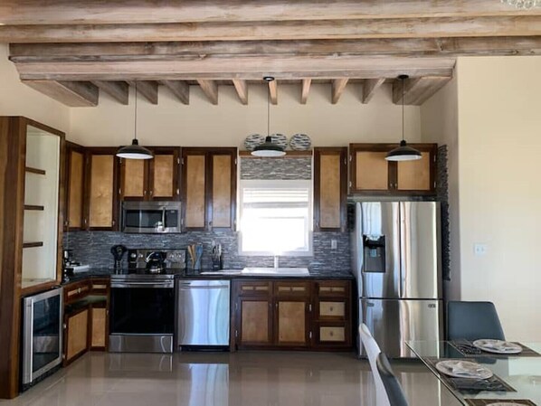 Una cocina moderna con armarios de madera, electrodomésticos de acero inoxidable e iluminación colgante.