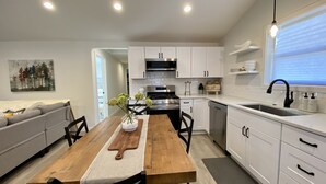 Une cuisine moderne avec des meubles blancs, une table à manger en bois et un four encastré.