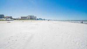 Una extensa playa de arena con edificios al fondo.