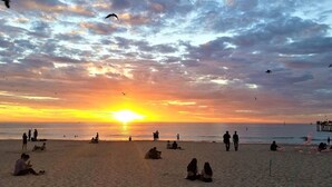 Una spiaggia al tramonto con persone che si rilassano e passeggiano sulla riva.