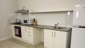 Una cucina compatta con forno a microonde, tostapane e lavello.