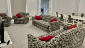 Un salon avec des canapés et des fauteuils à motifs, une table à manger et un téléviseur.