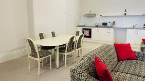 Un espacio habitable compacto con zona de comedor, kitchenette y sofá con tapicería estampada.