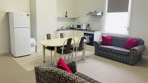 Un espacio habitable compacto con kitchenette, comedor y sofá.