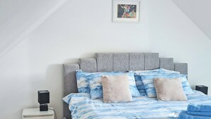 A bedroom with a bed, a bedside table, a speaker, and a framed artwork on the wall. - 3 bedroom accommodation in Johnston, near Haverfordwest (Johnston, near Haverfordwest)