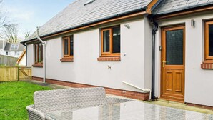 A house with a glass table and wicker chairs in the yard. - 3 bedroom accommodation in Johnston, near Haverfordwest (Johnston, near Haverfordwest)