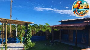 Un jardin à l’arrière de la maison, agrémenté d’une pergola en bois, d’une balançoire et d’un petit potager.