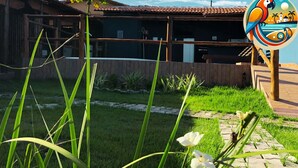 Un bâtiment avec un toit recouvert de tuiles, une clôture en bois et une pelouse parsemée de fleurs blanches.