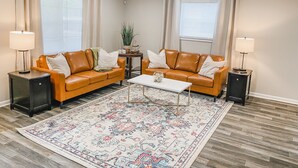 Un salon avec deux canapés en cuir, une table basse et un tapis à motifs.