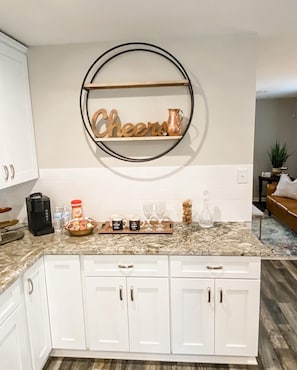 Enjoy a warm and inviting space with a fully equipped kitchen featuring a sleek cabinetry, granite countertop, and a decorative shelf.