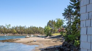 En kustvy med en stenig strand, en liten brygga och båtar.