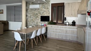 A modern kitchen with a stone backsplash, wooden cabinets, and a built-in island with seating. - Casa Lupita (Bolaños de Calatrava)
