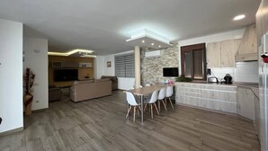 A modern kitchen with a dining area, built-in appliances, and a stone accent wall. - Casa Lupita (Bolaños de Calatrava)