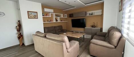 Una sala de estar moderna con un sofá, una mesa de centro y un televisor de pantalla plana.