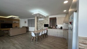 A modern kitchen with a dining area, built-in appliances, and a stone accent wall. - Casa Lupita (Bolaños de Calatrava)