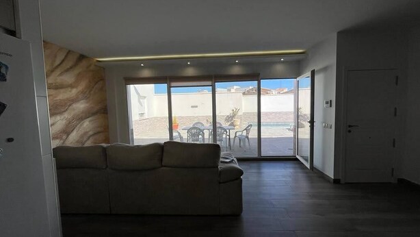 A modern living room with a sofa, a large window, and a view of the outdoors. - Casa Lupita (Bolaños de Calatrava)