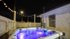 A hot tub with a blue light, surrounded by a wooden fence and a house. - 5 mins to DT, family friendly, hot tub, arcade, sleeps 8, fully fenced yard. (Chattanooga)