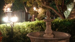Una fuente de piedra con barandilla en un jardín bien iluminado.
