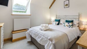 A bedroom with a bed, a window, a radiator, a TV, and a picture on the wall.