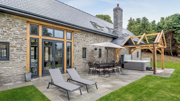A stone house with a patio, outdoor seating, and a hot tub.