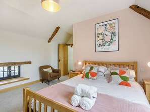 A bedroom with a wooden bed, a chair, a bedside table, a lamp, and a window with a view. - 5 bedroom accommodation in New Radnor, near Presteigne (New Radnor, near Presteigne)