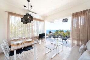 A dining area with a table set for four, a TV, and a grill outside.