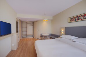 A hotel room with a bed, a desk, a chair, a TV, and a wardrobe. - Hanting Hotel (Nanjing)