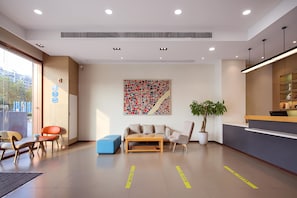 A modern hotel lobby with a reception desk, seating area, and a large abstract artwork on the wall. - Hanting Hotel (Nanjing)