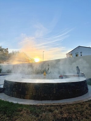 A stone fountain with a duck sculpture, surrounded by a stone wall and a paved walkway. - Pro Putting Green, Spa, Pool, Outdoor Kitchen (Chandler)