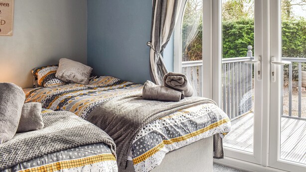 A bedroom with a bed, a window with curtains, and a view of the outdoors. - 2 bedroom accommodation in Walwen, Lixwm (Walwen, Lixwm)