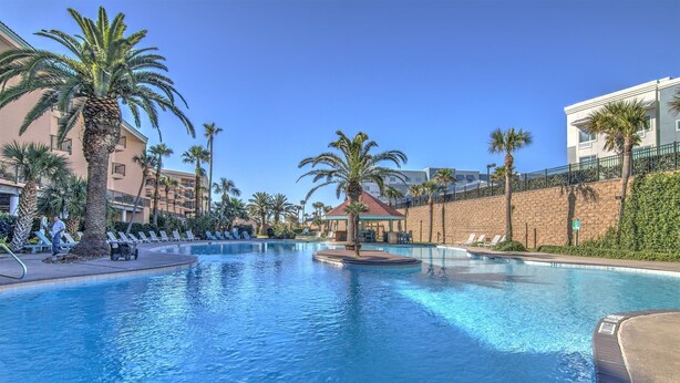 Una piscina con lettini e palme.