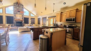 A spacious kitchen with a stone fireplace, wooden cabinets, and a large island. - Private and secluded mountain cabin (Cedar City)