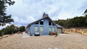 A modern house with a stone chimney, large windows, and a gravel driveway. - Private and secluded mountain cabin (Cedar City)