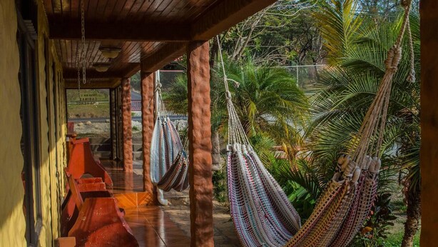 A covered outdoor area with hammocks and a tiled floor. - El Nido Lodge (Monteverde)