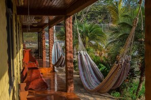 A covered outdoor area with hammocks and a tiled floor. - El Nido Lodge (Monteverde)