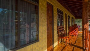 A covered corridor with large windows, wooden benches, and a tiled floor. - El Nido Lodge (Monteverde)