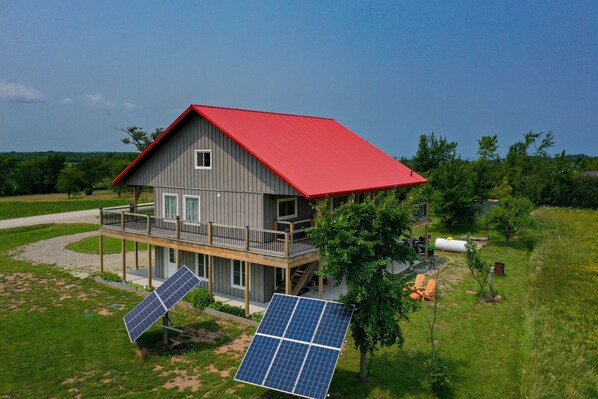 Ein zweistöckiges Haus mit rotem Dach, einem Balkon und Solaranlagen.
