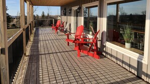 A wooden deck with red chairs and a potted plant. - Red Roof Chalet in close proximity to beaches, trails, golf and Blue Mountains. (Meaford)