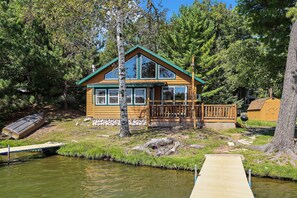 A cabin with a wooden deck, a dock, and a pond. - Stepaway Vacation Rentals - Carefree Creek Cabin (Saint Germain)
