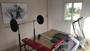 A gym with a bench press, a treadmill, and a stationary bike. - Comfortable apartment with garden access and weights room (Mardié)