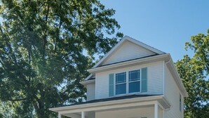 A two-story house with a covered porch and a front yard.