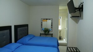 A bedroom with a bed, a mirror, a TV, and a small table with a plant. - Hotel Mar Caribe (Puerto Vallarta)