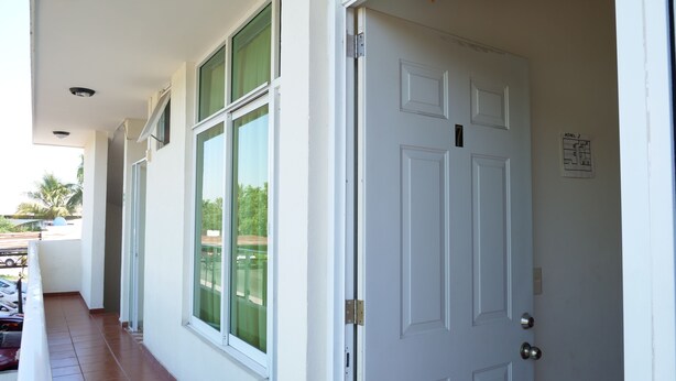 A white door with a metal latch, a window with green curtains, and a small sign indicating "Level 2" on the wall. - Hotel Mar Caribe (Puerto Vallarta)