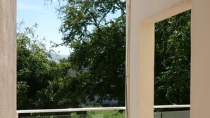 A balcony with a glass railing, a tiled floor, and a view of greenery and trees. - Hotel Mar Caribe (Puerto Vallarta)