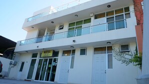 A two-story building with a sign indicating it is a hotel. There are multiple windows with curtains, a balcony on the upper floor, and a door with a sign that says "ABIERTO". - Hotel Mar Caribe (Puerto Vallarta)