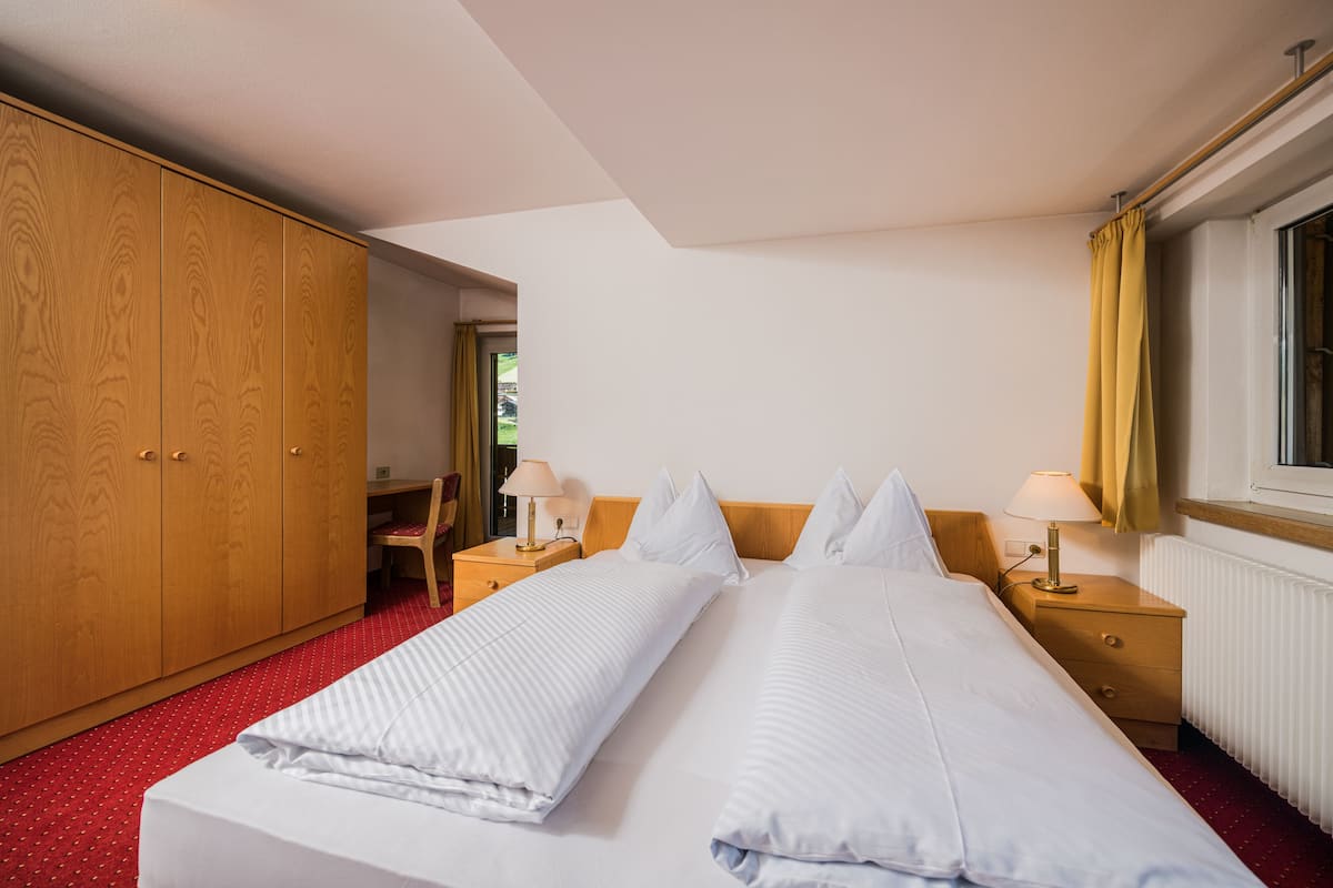 Ein Hotelzimmer mit einem großen Bett, einem Holzschrank, zwei Nachttischen mit Lampen und einem Fenster mit Vorhängen.