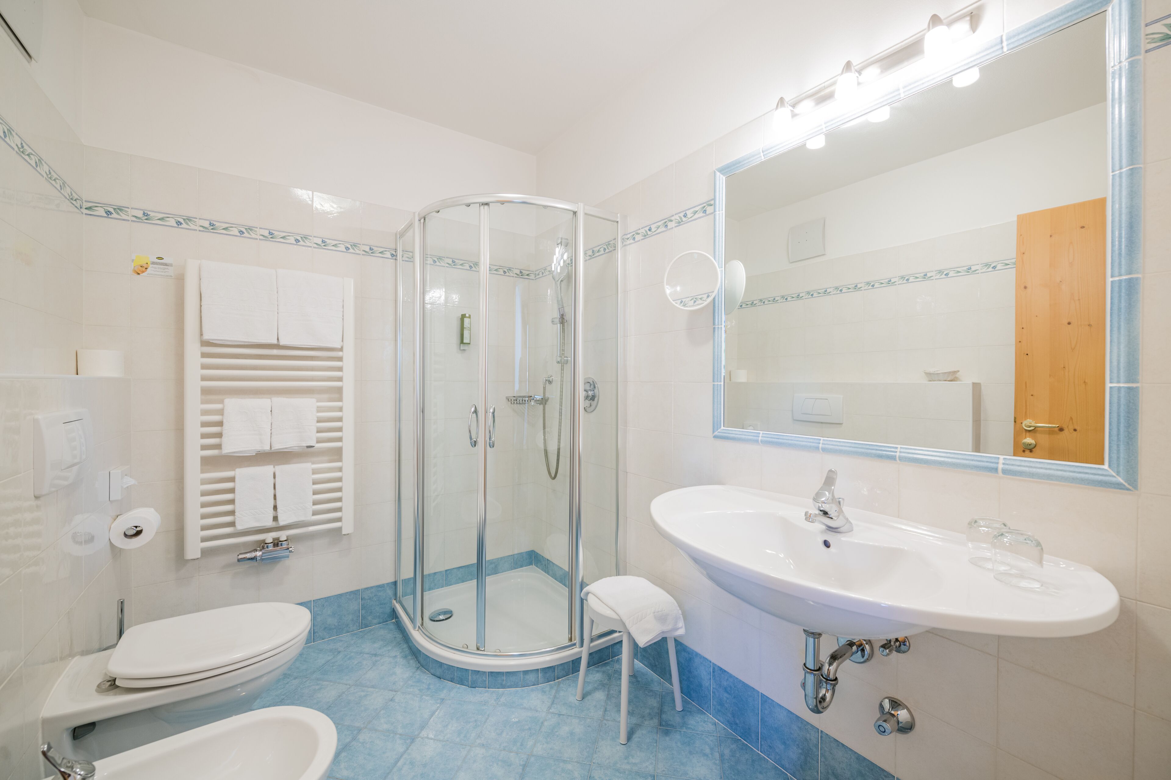 Un bagno moderno con doccia vetro, lavandino bianco e water.