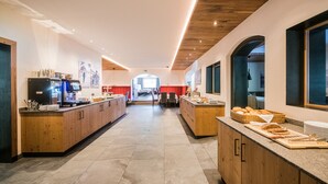 Une cuisine moderne avec des meubles en bois, un îlot central où sont disposés des aliments, et une vue sur l’espace repas.