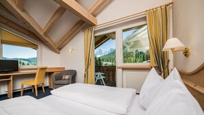 Une chambre d’hôtel équipée d’un lit, d’un bureau, d’une chaise, d’une télévision et d’une fenêtre avec des rideaux.
